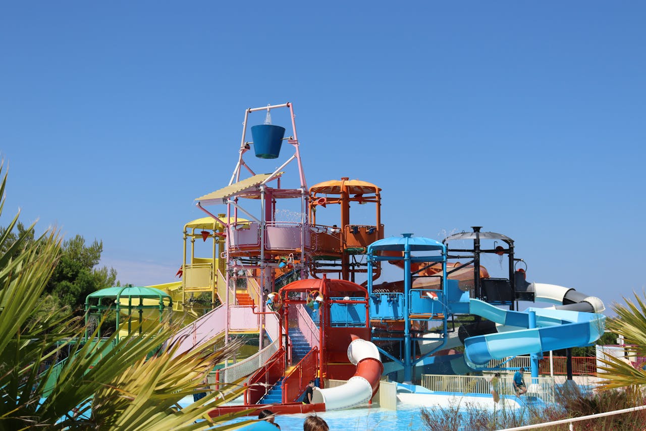 Colorful waterslides at an outdoor aquapark on a sunny summer day.